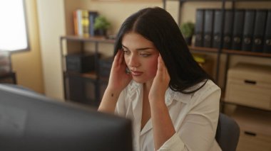 Ofis ortamında başı ağrıyan bir kadın, raflar ve evrak işleriyle çevrili, çeşitli ofis dekorları ve elementlerle iş ortamında stres taşıyor..
