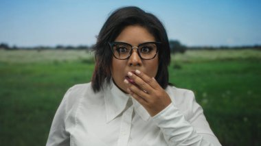 Park yerinde, şaşırmış bir ifade, gözlük, beyaz gömlek, arka plan, duygusal tepki, genç yetişkin, açık hava, yeşil çimen, şaşkın görünüyor.