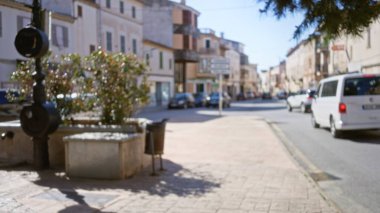 Güneşli bir günde, dağılmış binaların ve yayaların arka planlarını gösteren eski bir Akdeniz kasabasındaki bulanık sokak manzarası..