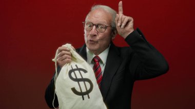 Kırmızı duvarda para çantası taşıyan kıdemli bir adam yozlaşmış iş anlaşmalarını simgeliyor..