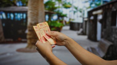 Meksika pesolarını elinde tutan bir adam şehirde yatırım fırsatları ve açık havada finansal işlemler sergiliyor..