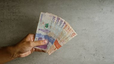 Elle tutulan Kolombiya pezoları somut bir zemine karşı, farklı para birimlerinin değerlerini gösteriyor