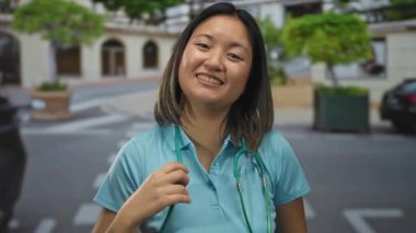 Steteskoplu genç bir kadın doktor şehir sokaklarında gülümsüyor, neşe ve güveni ifade ediyor, şehir çevresi ve yeşilliklerle çevrili..