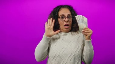 Mısırlı orta yaşlı bir kadın elinde Mısır banknotları tutuyordu, soyutlanmış mor bir arka plana şaşırmış görünüyordu, finansal temalar ve duygular vurguluyordu.