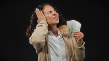 Orta yaşlı bir kadın siyah arka planda gürültüye karşı Singapur doları tutuyor, para ile stresi taşıyor..