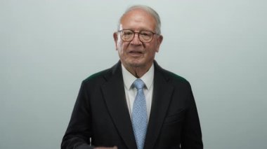 Takım elbiseli kıdemli işadamı tek eliyle ağzını kapatıyor, beyaz arka planda izole edilmiş, bir şirket ortamında şaşkınlık, duygu ve düşünce ifade ediyor..