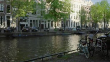 Amsterdam Hollanda 'daki bulanık kanal manzarası. Berrak suların altında, sakin bir Avrupa kentsel manzarasının özünü yansıtan bisikletler var..