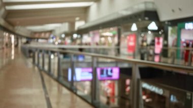 Bulanık alışveriş merkezi koridoru, parlak dükkan önleri ve yumuşak odaklı ışıklar modern bir mağaza ortamında dağıtılmış ve bokeh etkisi yaratıyor.