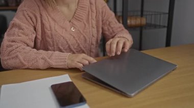 Ofis ortamında dizüstü bilgisayarda çalışan pembe kazaklı bir kadın rahat ama profesyonel bir çevreyi ön plana çıkarıyor..