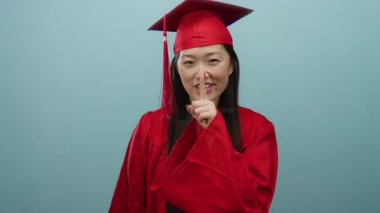 Kırmızı mezuniyet elbisesi giymiş bir kadın mavi arka plana karşı 