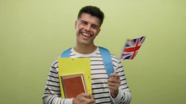 Sarı arka planda Birleşik Krallık bayrağıyla gülümseyen bir adam sırt çantası takan kitapları tutuyor.