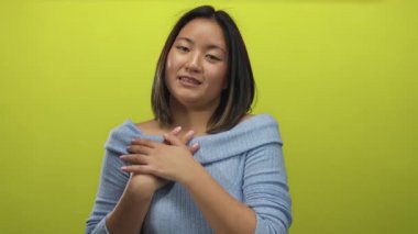 Parlak sarı arka planda gülümseyen kadın nazikçe ifade ve katlanmış ellerle sıcaklığı ve mutluluğu iletir.