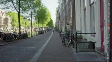 Amsterdam 'ın ikonik kanal caddelerinin bulanık görüntüsü bisiklet ve mimariyle kaplı, sakin kentsel ambiyansı odaksız bir perspektifle yakalıyor..