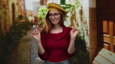 Açık havada gülümseyen, bereli ve gözlüklü bir kadın.