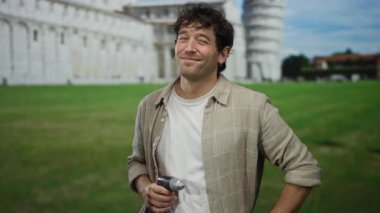 İspanyol adam sidik kulesinin önünde tornavida tutuyor, arka planda yeşil çimlerle güvenle gülümsüyor, seyahat ve inşaat temalarının bir karışımını sergiliyor..