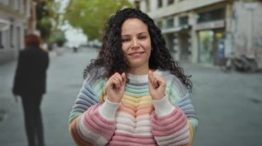 Şehir caddesinde renkli süveter giyen, dışarıda neşe saçan, hayat dolu bir şehir atmosferinde İspanyol mirası sergileyen bir kadın..