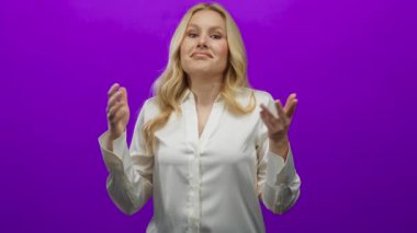 Canlı mor bir arkaplan önünde omuz silken bir kadın, rahat ve rahat bir ifadeyle beyaz bir bluz giyiyor..