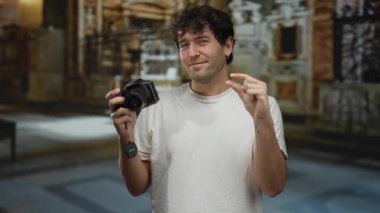 İspanyol adam sanat galerisi ortamında fotoğraf ve ifadeyi müze zeminiyle harmanlayarak yaratıcı bir atmosfer yakalayan küçük bir jest yapıyor..