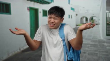 Sırt çantalı genç bir adam, beyaz gömlek giyiyor, gün boyunca kargaşa ve belirsizlik taşıyor..