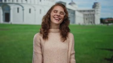 İtalya 'da güneşli bir günde arka planda ikonik kulesi olan Pisa' nın yanında neşeli bir şekilde gülümseyen genç kadın..