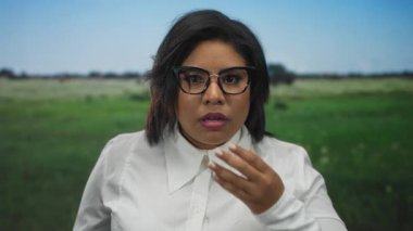 Park yerinde, şaşırmış bir ifade, gözlük, beyaz gömlek, arka plan, duygusal tepki, genç yetişkin, açık hava, yeşil çimen, şaşkın görünüyor.