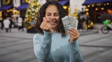 Peru 'da orta yaşlı bir kadın şehir caddesinde Peru tabanı tutarken parmaklarıyla kalp hareketi yapıyor..