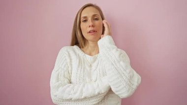 Pembe arka planda sıkılmış genç bir kadın, kolları çapraz bağlanmış süveter giyen sarışın, sorunları ve depresyonu düşünen.