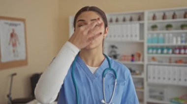 Klinik odasında steteskoplu mavi üniformalı İspanyol kadın doktor tıbbi malzemelerle çevrelenmiş vazifelerini yerine getiriyor..