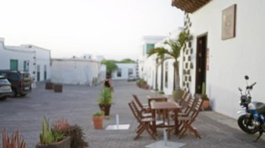 Bulanık kadın masalar, sandalyeler, Lanzarote 'deki bitkiler ve motorsikletle dışarıda yürüyen İspanya' nın kanarya adaları.