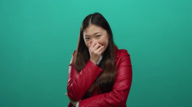 Canlı yeşil arka planda gülen bir kadın kırmızı ceket giyiyor rahat ve neşeli görünüyor, neşeli bir anı yakalıyor..