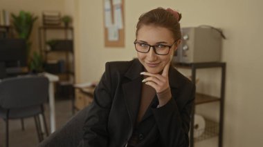 Modern dekorlu şık ofis ortamında gülümseyen bir kadın profesyonel bir iş ortamında kendine güvenen bir iş atmosferi yakalıyor..