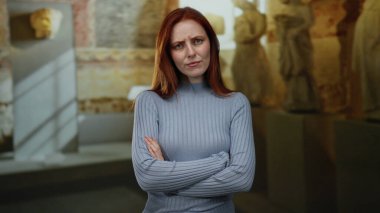 Kilisede kollarını bağlayan, ciddi ifadeleri olan, arka planda tarihi heykeller olan, kızıl saçlı güzel ve yetişkin beyaz yüzlü bir kadın..