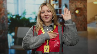 Otelde gönüllü olarak çalışan bir kadın, bağlılık ve bağlılığını ifade ederken kapalı alanda kırmızı yelek giydiğine dair yemin ediyor..