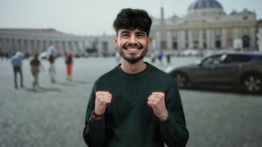 Genç adam, arka planda Aziz Peter Bazilikası ile Vatikan 'da neşeyle gülümsüyor, ikonik bir kent ortamında mutluluk ve turizm taşıyor..