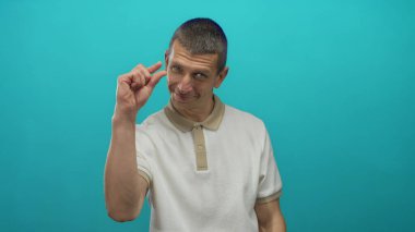 Beyaz gömlekli adam, küçük boyutta veya minimum konsept ifade eden izole edilmiş mavi duvara karşı küçük bir jest yapıyor..