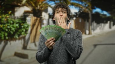 Elinde Rus rublesi tutan İspanyol bir adam ağaçlar ve şehir manzarasıyla çevrili güneşli bir şehir caddesinde şok geçirdi..