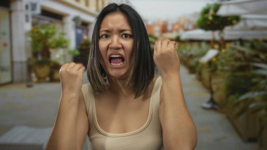 Canlı bir şehir sokağında öfkesini yumruklarıyla ifade eden bir kadın. Etrafı bulanık şehir geçmişiyle çevrili. Açık havada hayal kırıklığı, enerji ve duygu aktarıyor..