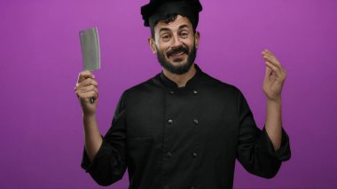 Siyah üniformalı İspanyol şef elinde satırla canlı mor arka planda aşçılık hevesine gülümsüyor..