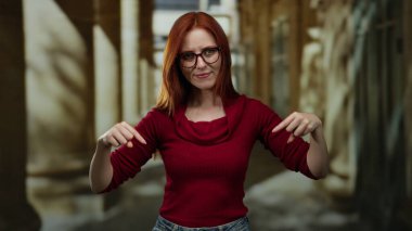 Tarihi üniversite koridorunda kırmızı kazak giyen kadın, entrika ve kararlılıkla vurgu ve konumu öneriyor..