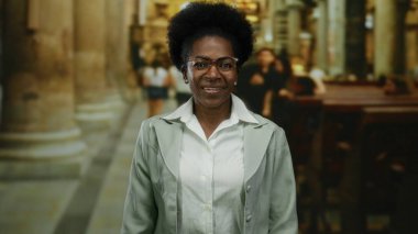 Kilisenin iç mekanında gülümseyen bir kadın, davetkar bir atmosferde modern ve geleneksel elementlerin karışımı aracılığıyla barış, kültür, inanç ve çeşitlilik sergiliyor..