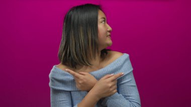 Genç bir kadın gülümsüyor ve pembe arka planda mavi kazak giyiyor neşeli duygular ve ifadeler aktarıyor.