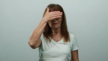 İspanyol kıdemli kadın gülümsüyor ve yüzünü beyaz bir duvara yaslıyor, neşe ve mizahı yansıtıyor..