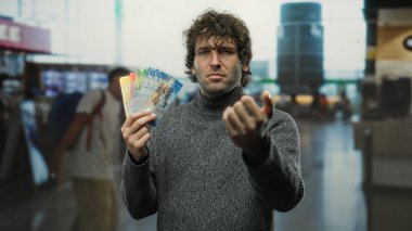 Havaalanı terminalinde elinde İsviçre frangı tutan bir adam ilginç bir finansal içerik sunuyor..