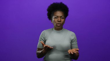 Canlı mor bir arkaplan karşısında el kol hareketi yapan bir kadın izole bir stüdyo ortamında iletişim ve duygu tasvir ediyor..