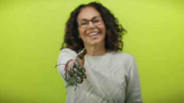 Gözlüklü bir kadın gülümseyip, parlak sarı bir arkaplan karşısında el sıkışırken arkadaşlığı ve renkli cazibeyle bağlantıyı vurguluyor..