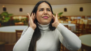 Restoranda jest yapan kulaklı bir kadın, kederli bir ifadeyle Latin kökenli Latin kökenli genç kahve sahnesini yakalıyor..