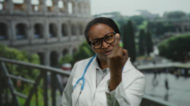 Roma Kolezyumu 'nun yanında gözlüklü kadın doktor. Roma' da steteskop ve beyaz önlük giymiş düşünceli görünüyor..