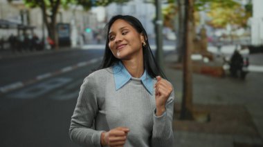 Canlı bir sokakta neşeyle dans eden genç bir kadın enerjik ruhunu ve neşeli ifadesini canlı bir atmosferle şehir ortamında sergiliyor..
