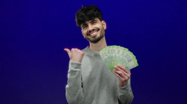 Mavi zemin üzerinde Rusya rublesi taşıyan bir adam, zenginlik ve güven gösterisi yapıyor..