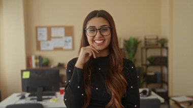 Ofis ortamında gülümseyen ve arka planda bitkiler olan bir kadın profesyonel bir çevre ve modern iş ortamı öneriyor.